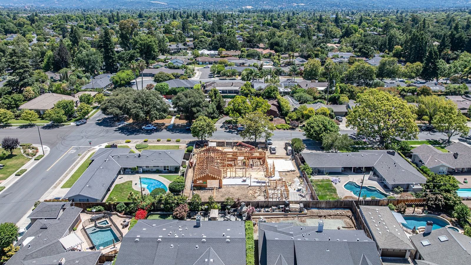 Aerial view of a large construction site surrounded by a suburban neighborhood and trees