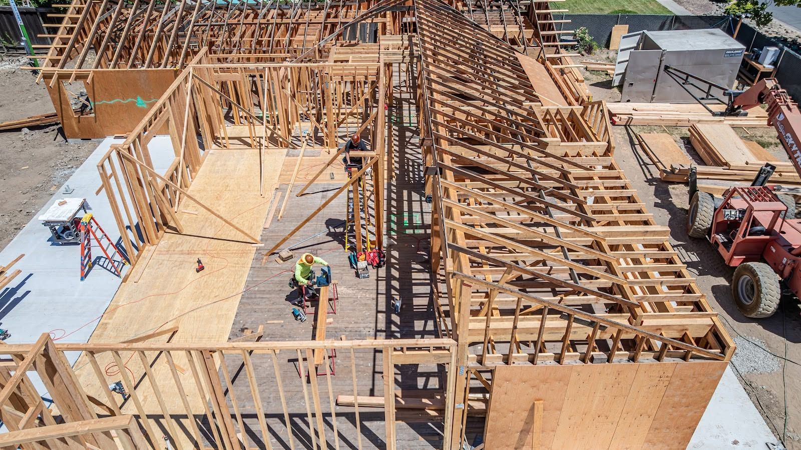Construction site with wooden framing and workers on a partially built structure