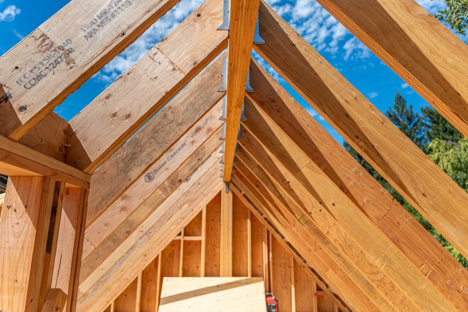 Wooden roof framing inside a house under construction against a blue sky