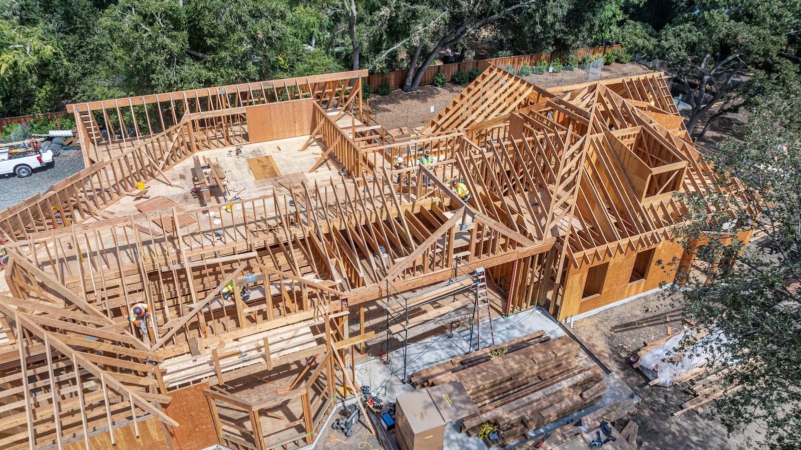 Partially built wooden house frame on a construction site, seen from above.