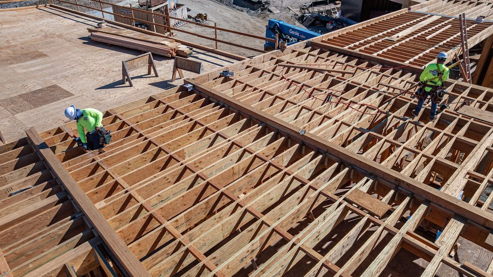 Construction workers setting rebar on a large concrete formwork structure at a building site