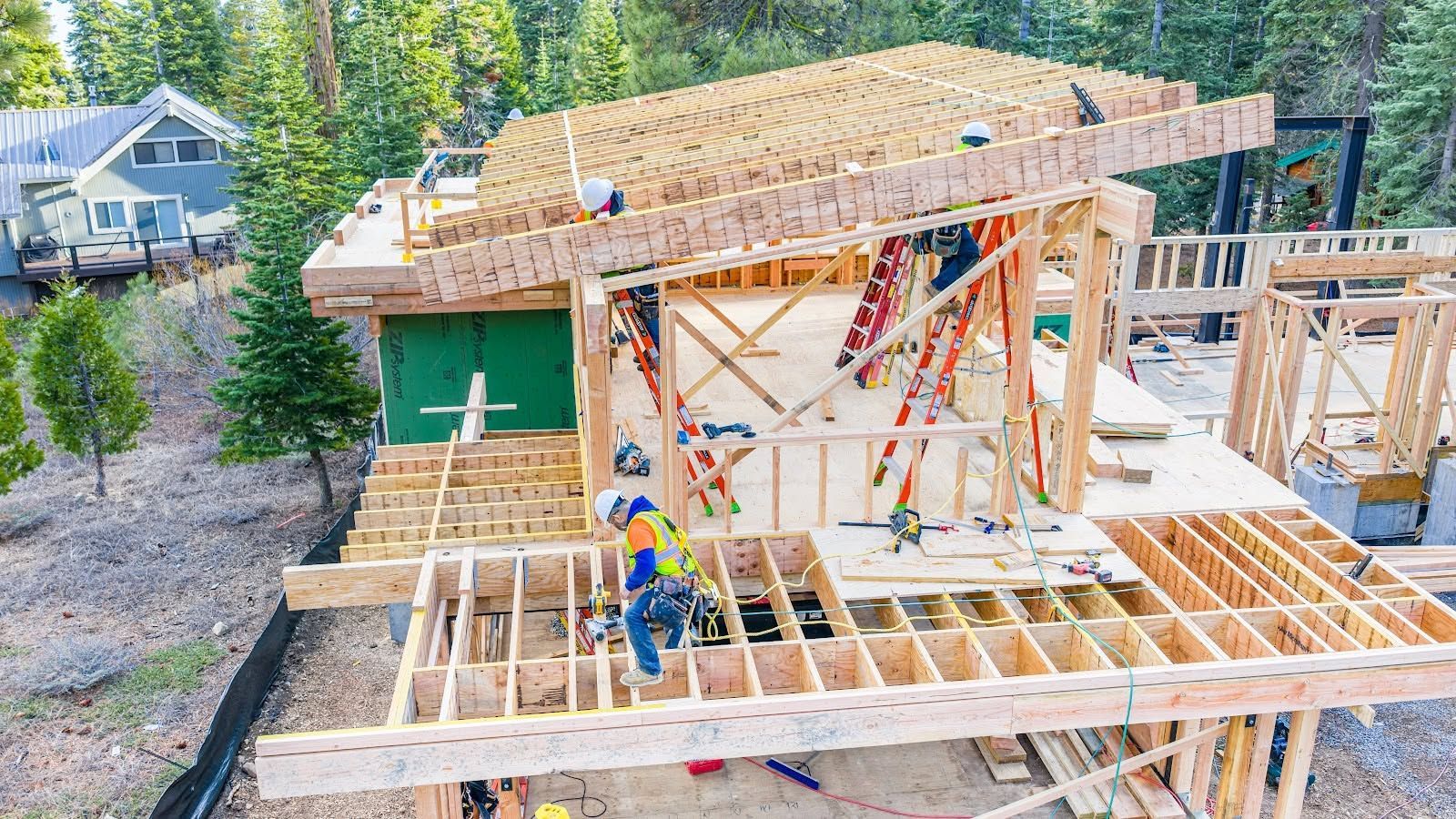 Construction workers framing a wooden house roof at a residential build site.