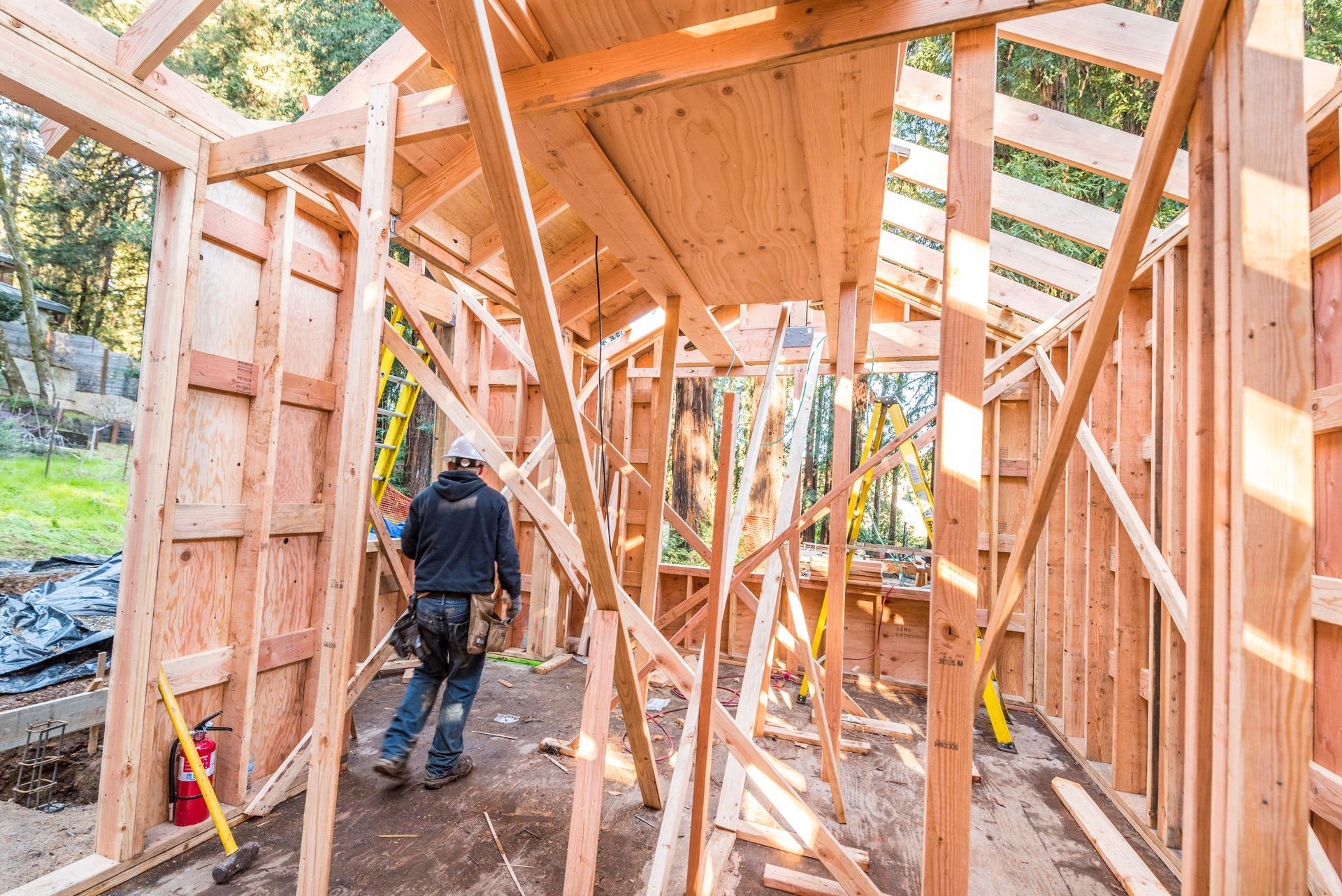 Worker framing a wooden structure inside a partially built house under construction