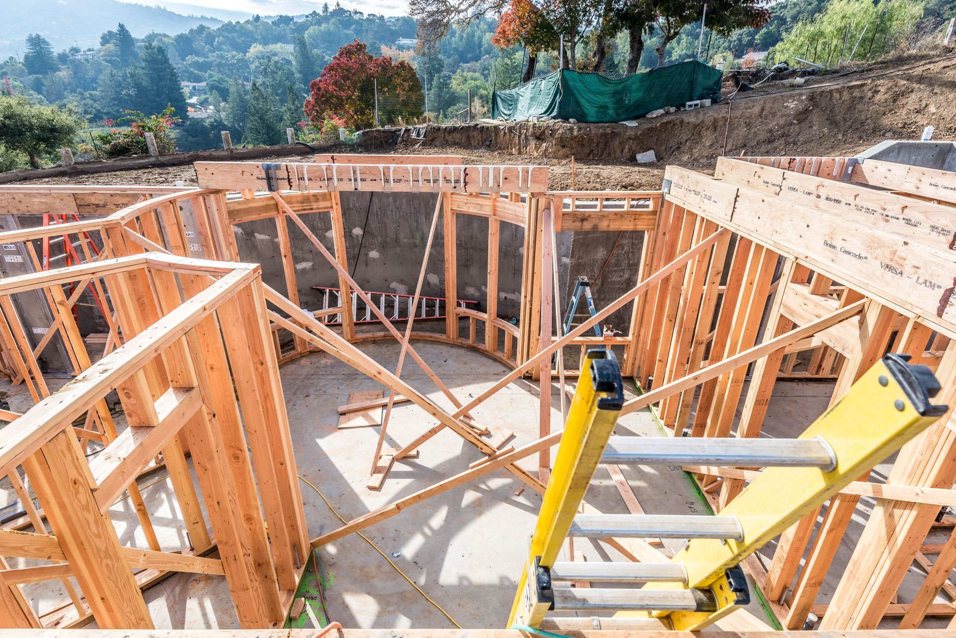 House foundation under construction with wooden framing and ladders on a hillside site