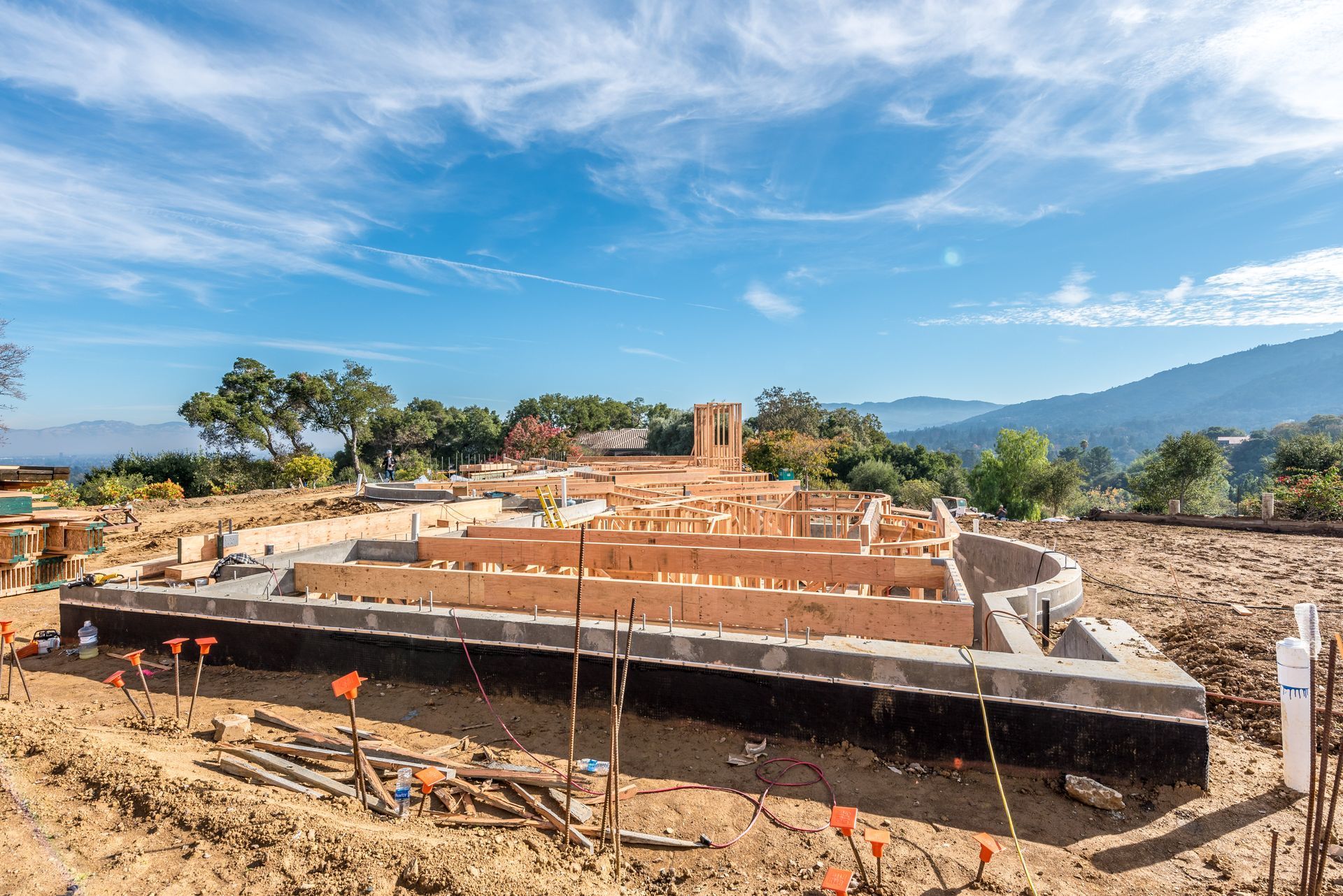 Construction site with a concrete foundation under blue sky and mountains in the background