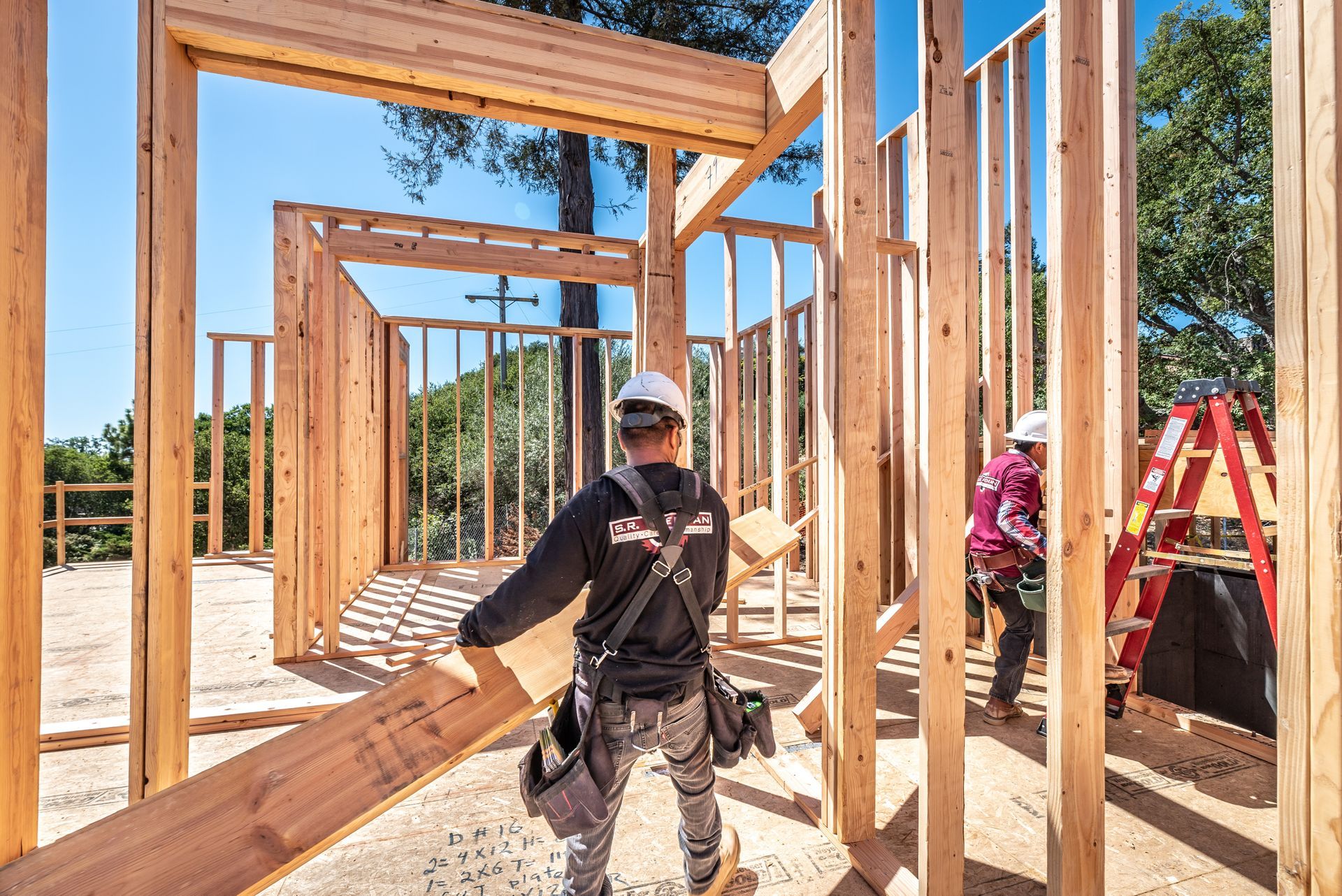 Construction workers framing a wooden house on a sunny building site
