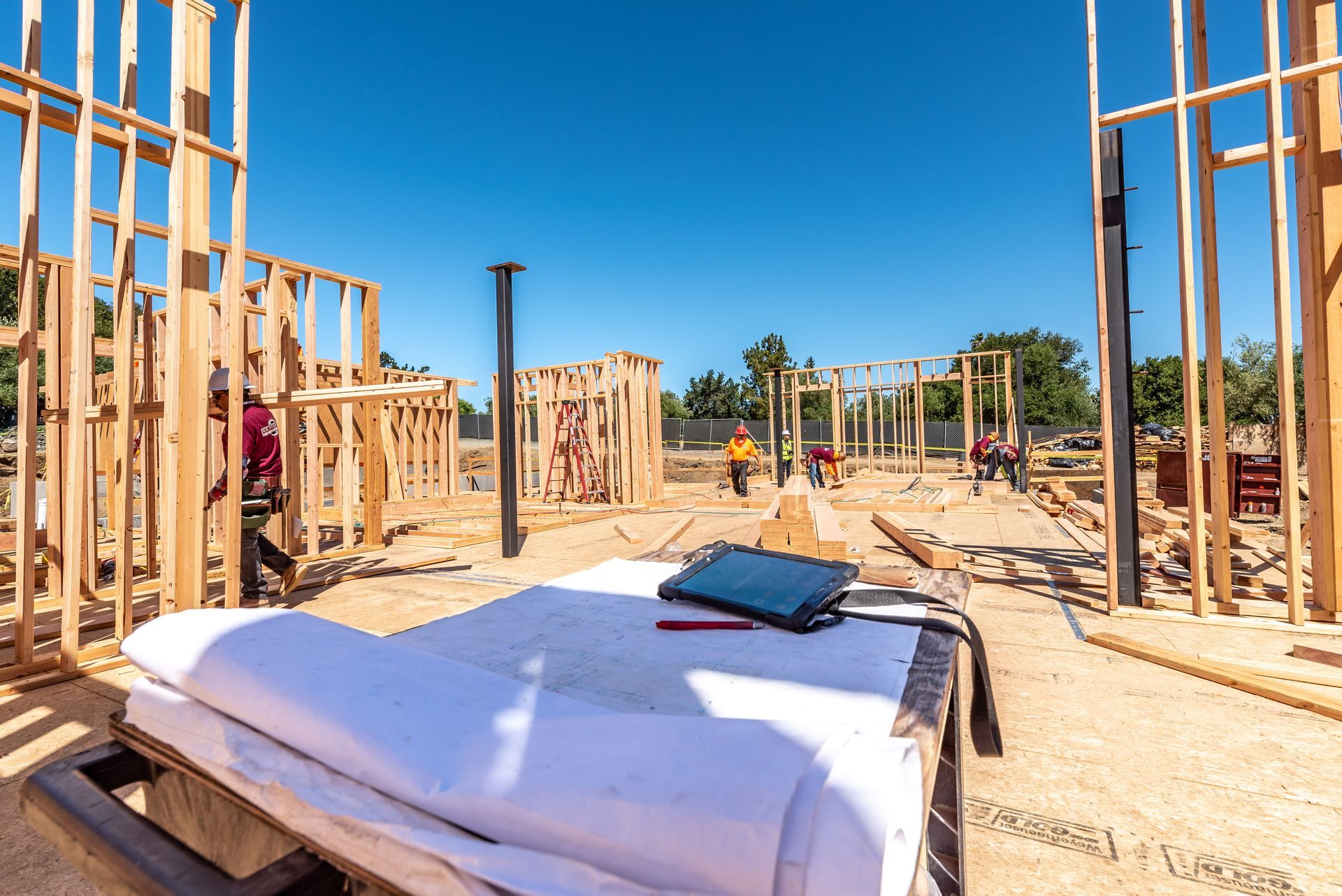 Partially framed house under construction with lumber walls, insulation panels, and blue sky.