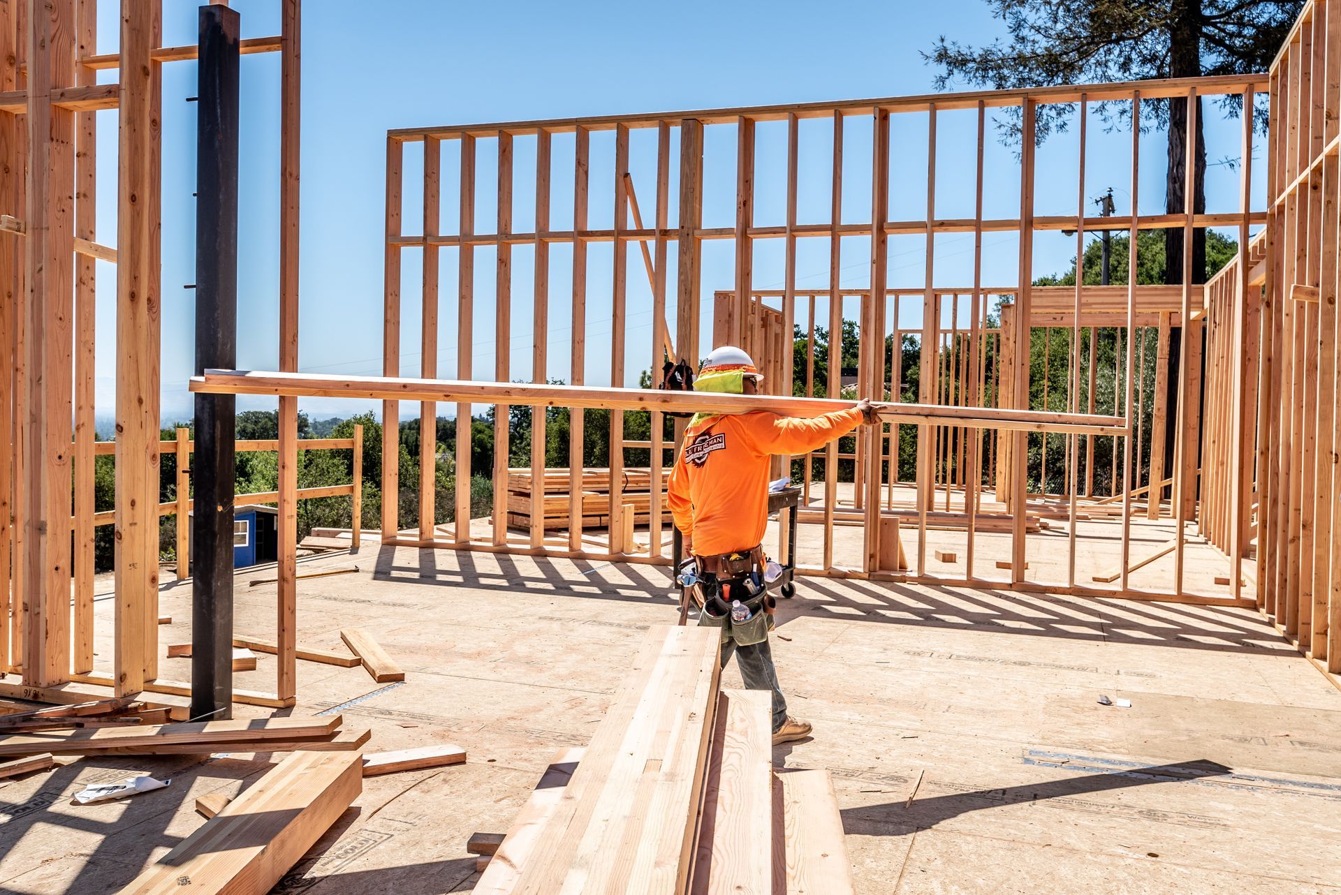 Construction worker framing a wooden house wall on a sunny site