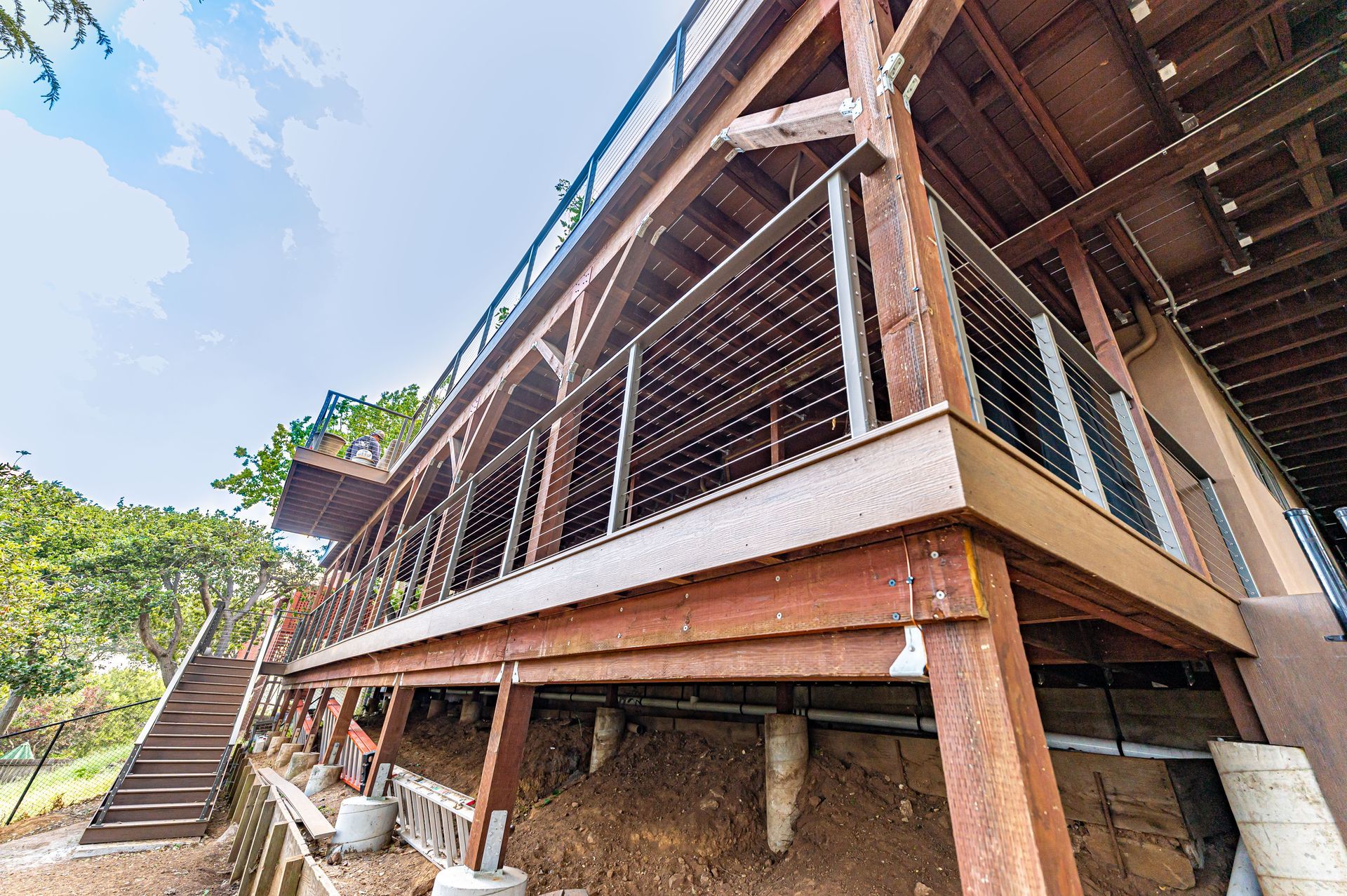 Wooden stilt building with stairs, balcony railings, and a sloped roof in a tropical setting