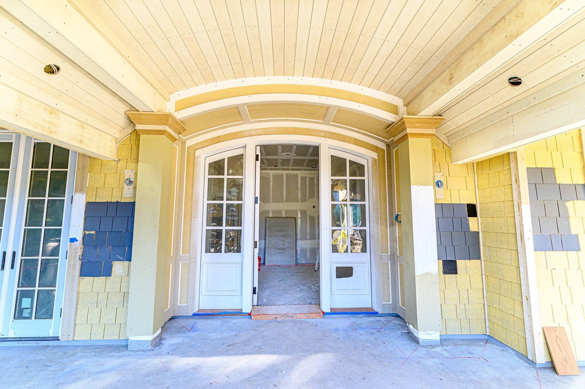 Yellow porch entrance with white French doors and tiled walls under a curved ceiling