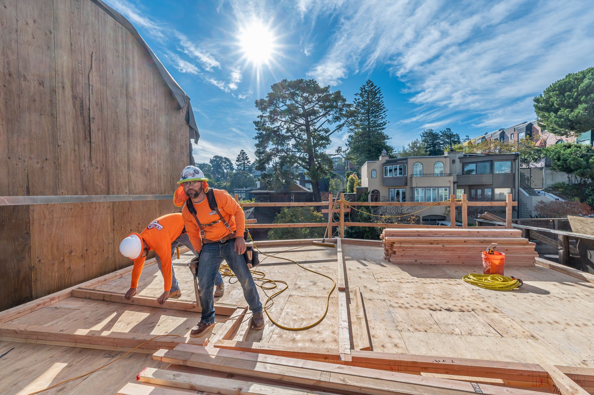 Construction workers pouring concrete on a rooftop under bright sunlight
