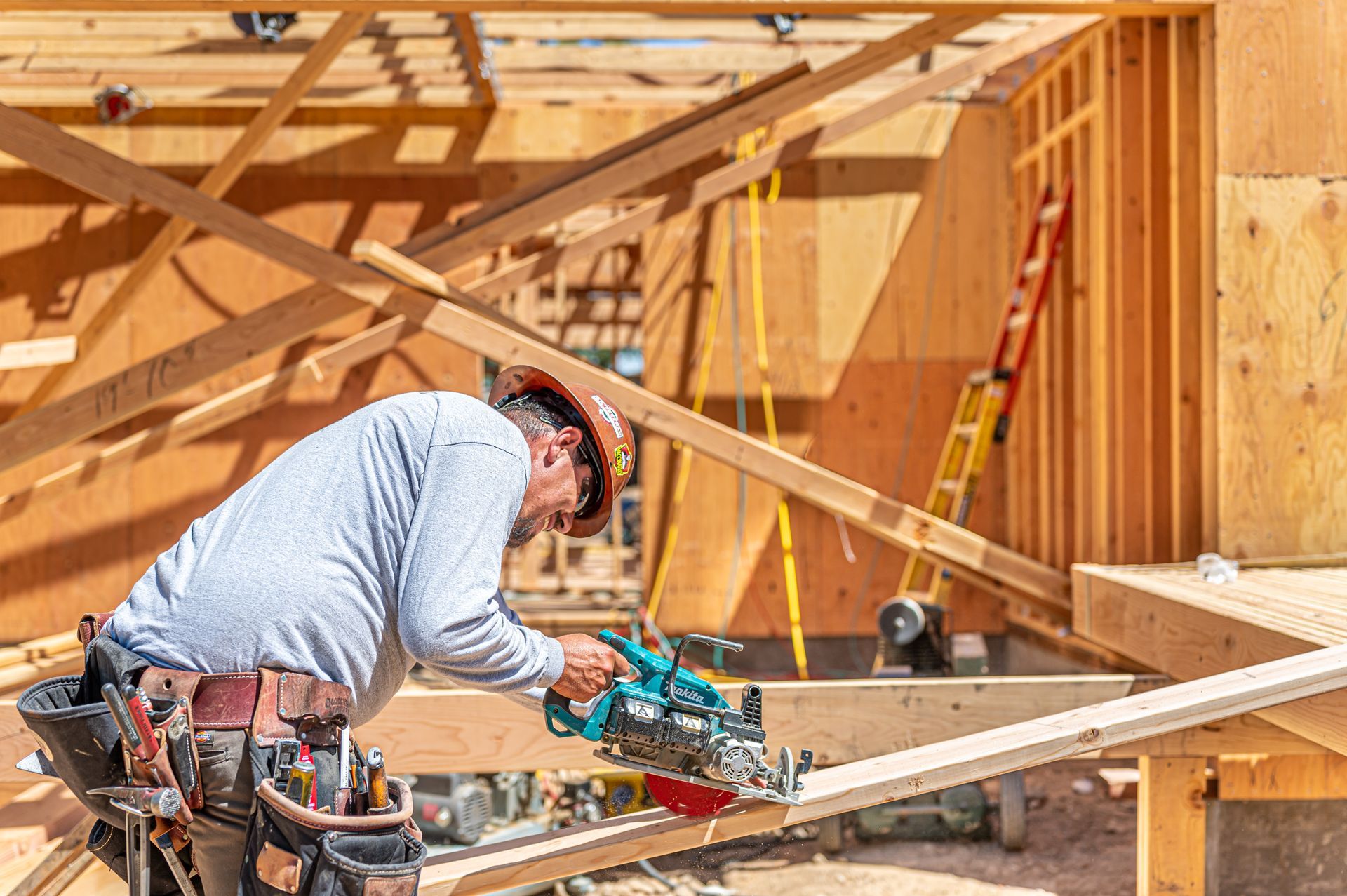 Construction worker measuring wood framing on a house under construction outdoors