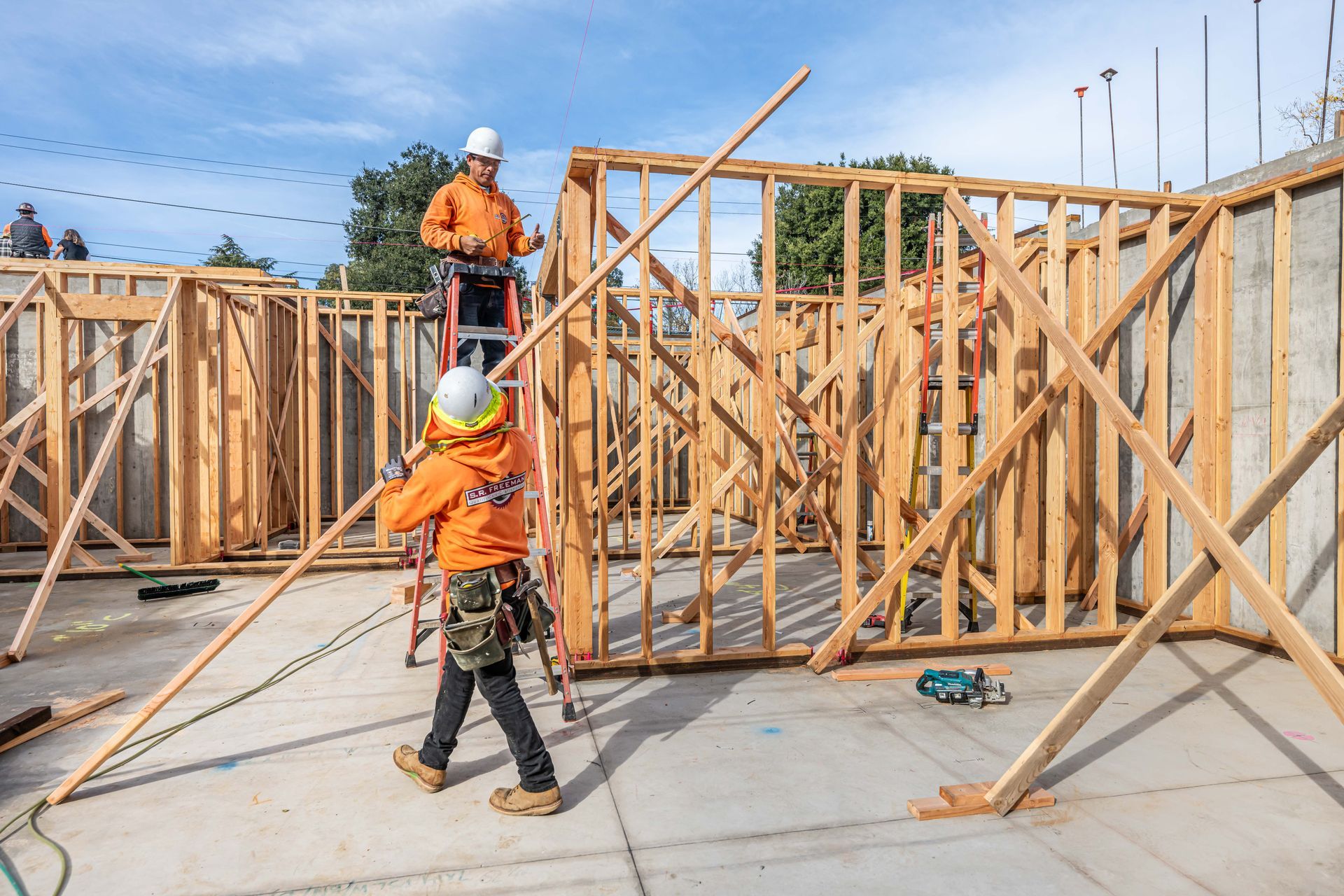 Construction workers framing house walls on a sunny job site