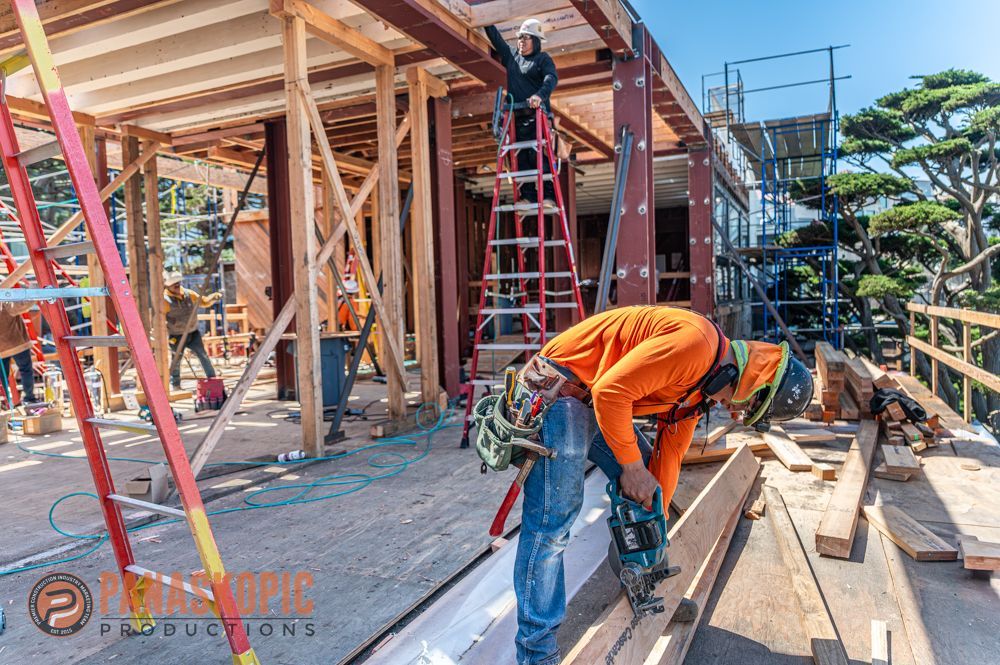 Construction workers on a wooden-framed building site, with ladders and scaffolding around them
