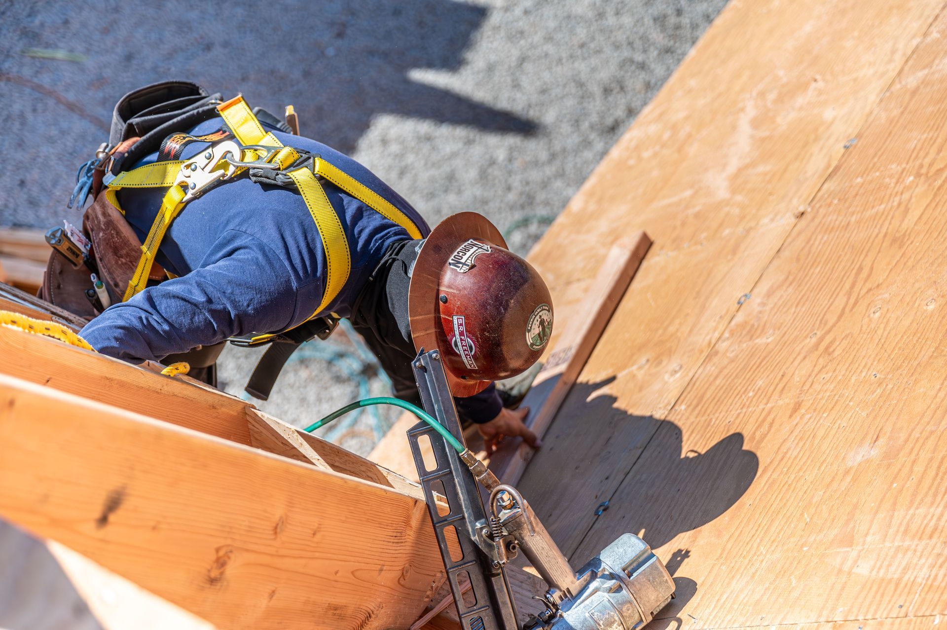 Worker in safety harness climbing a wooden wall with a rope and tool belt