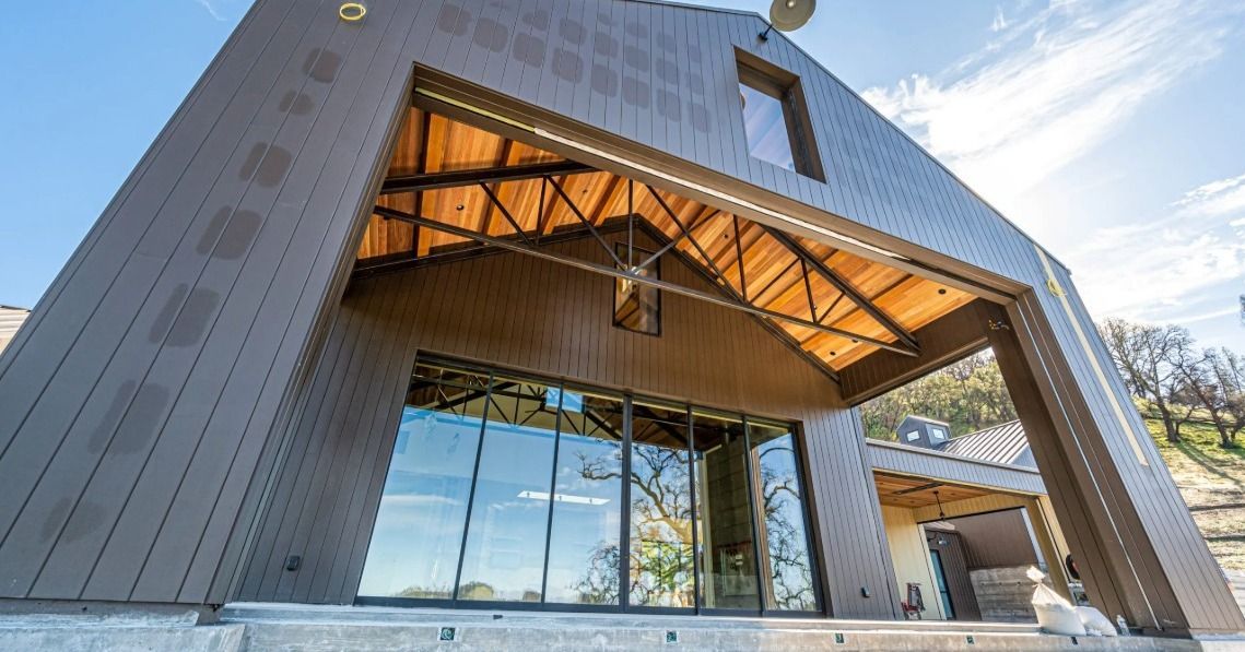 Modern building entrance with large glass facade and wood-paneled overhang under blue sky