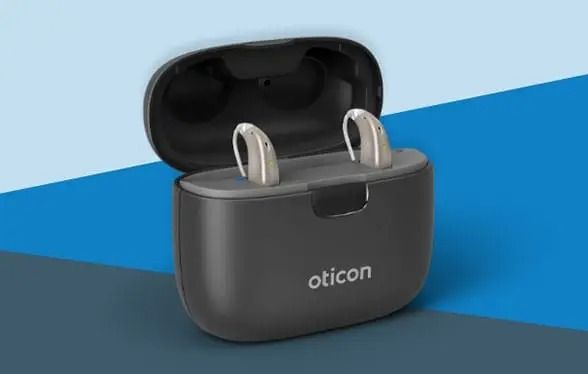 Audífonos Oticon en un estuche de carga negro abierto sobre un fondo azul.