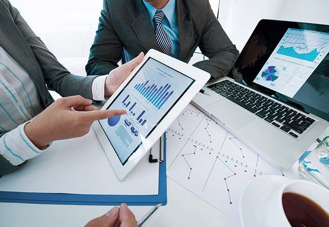 A man is pointing at a tablet with a graph on it
