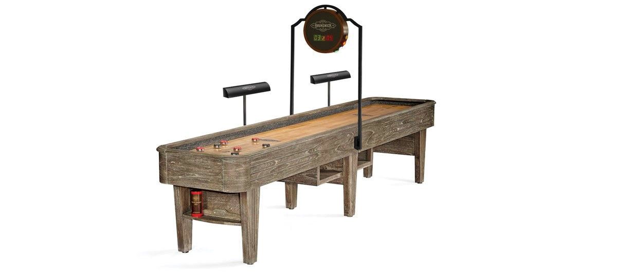 A rustic wooden shuffleboard table with a scoreboard and cue sticks on a white background