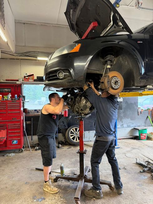 Car on wheel alignment machine with clamps attached to both front wheels in a garage.