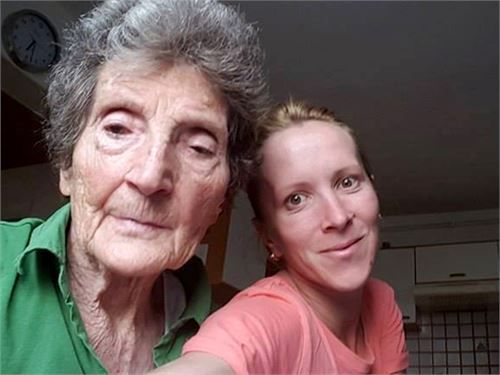 Ältere und jüngere Frau lächeln; drinnen, möglicherweise ein Selfie.