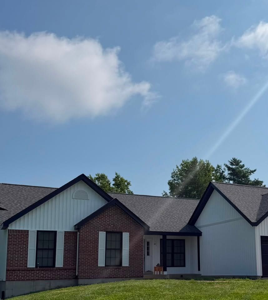 Single-story suburban house with brick and white siding under a blue sky with clouds Single-story suburban house with brick and white siding under a blue sky with clouds