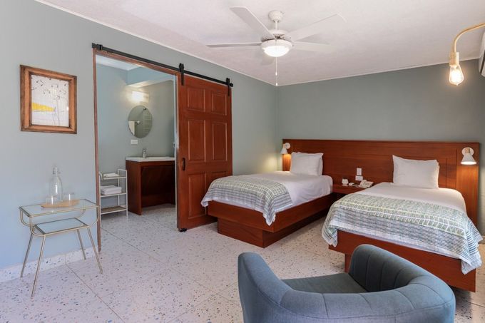 A hotel room with two beds , a chair and a ceiling fan.