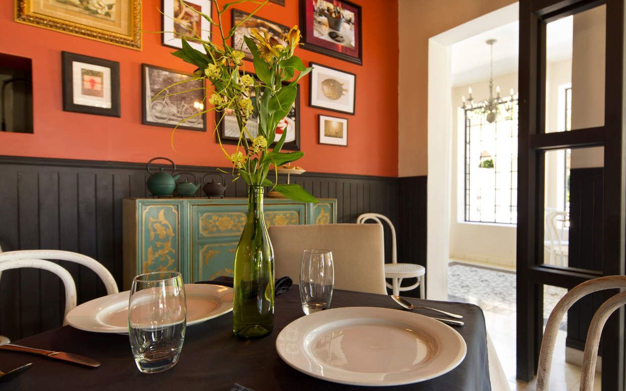 A dining room table with plates , glasses , and a vase of flowers on it.