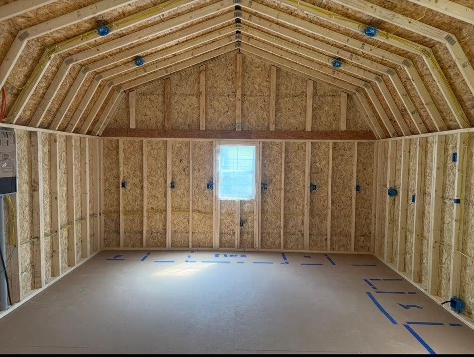 Unfinished attic room with exposed wood framing, insulation, and a small window.
