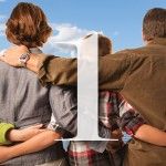 Family with arms around each other, looking out at a blue sky. A white number one is in front of them.