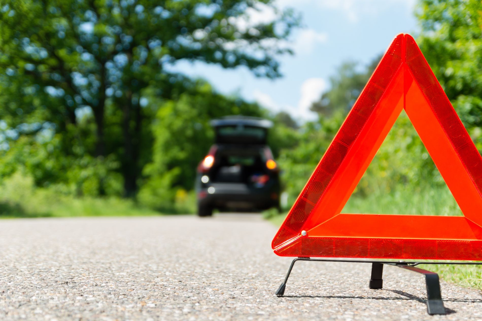 Un triangolo rosso è posizionato sul ciglio della strada accanto a un'auto.