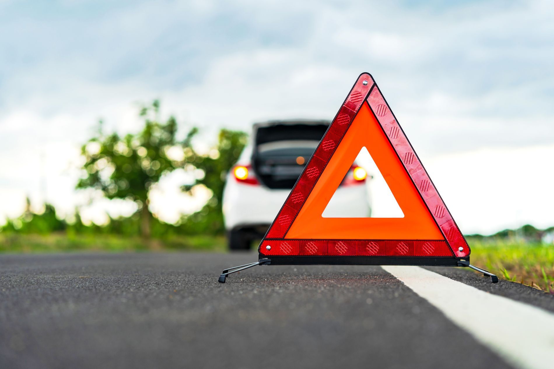 Un triangolo rosso è posizionato sul ciglio della strada accanto a un'auto.
