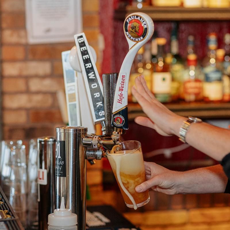 A person is pouring beer from one of the many import and domestic beer taps.