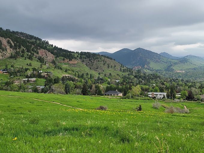 A green field with mountains in the background and a cloudy sky