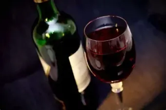 Wine bottle and glass filled with red wine.