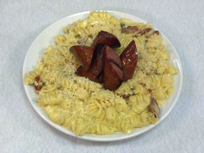 A white plate topped with macaroni and cheese and sausage.