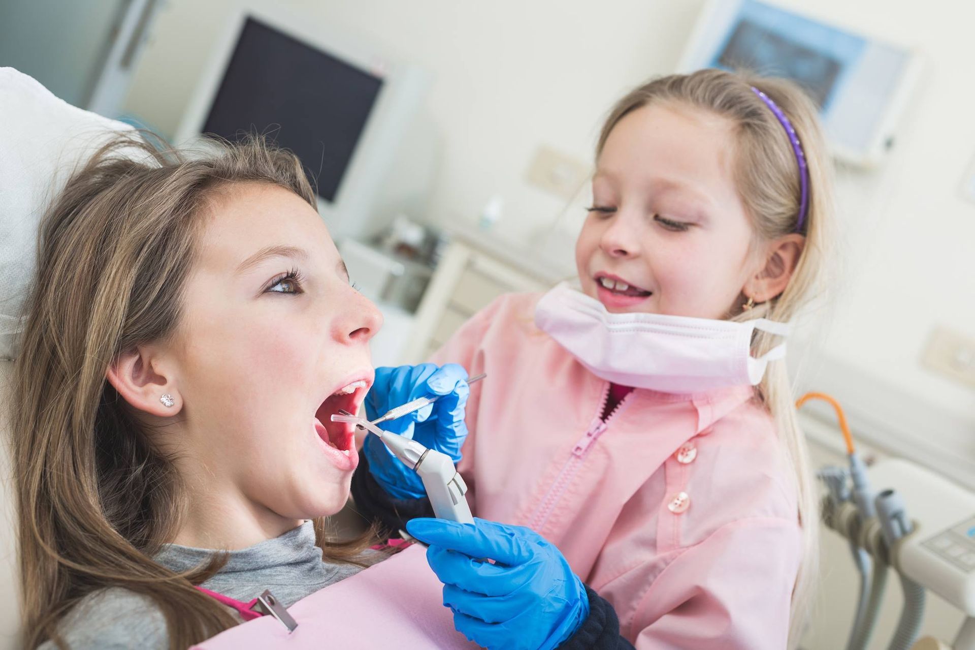 Girl Pretending to Be a Dentist Examining Another Girl's Teeth — Trinity Beach Dental In Trinity Beach, QLD