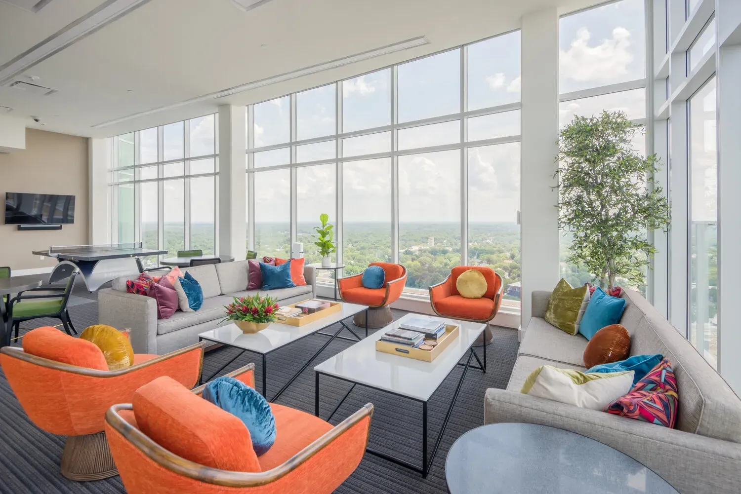 Modern lounge area with sofas, accent chairs, and large windows overlooking a city skyline.