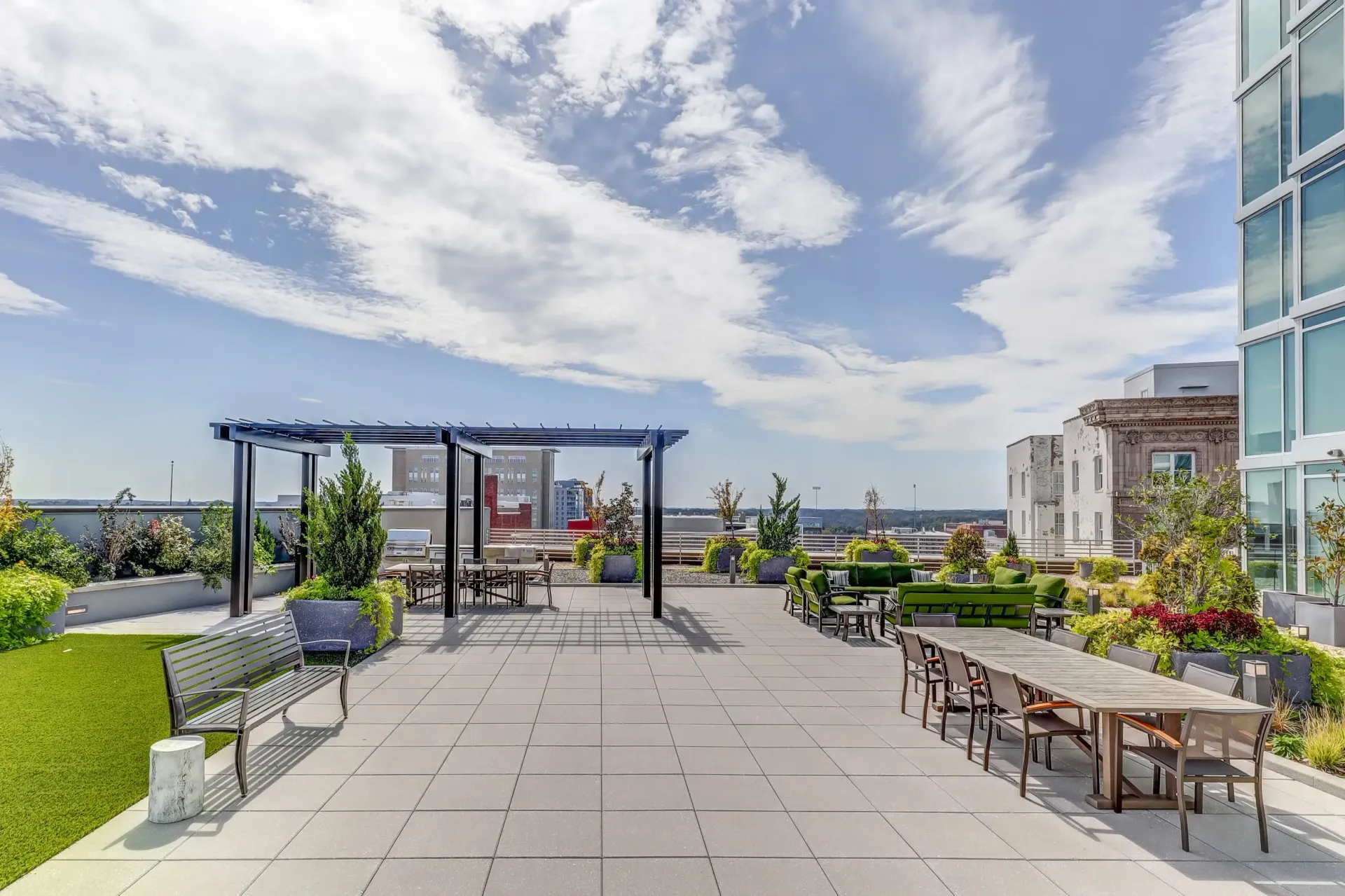 Rooftop terrace with seating, tables, and pergolas overlooking a city skyline.