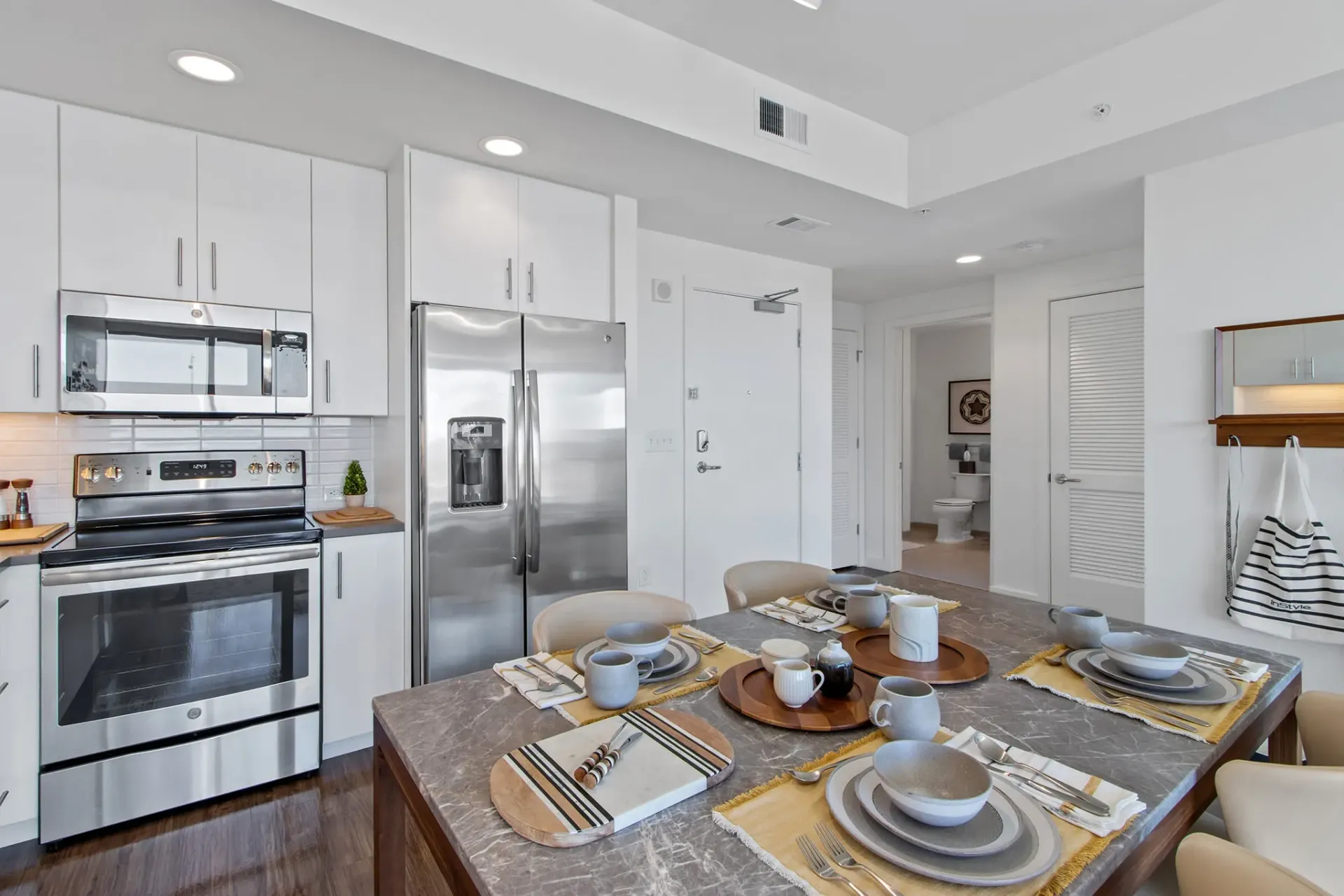 Dining area and kitchen in an apartment with stainless steel appliances and a table set for four.