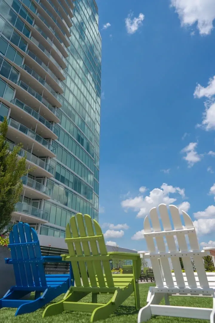 Adirondack chairs on a rooftop with a modern apartment building in the background