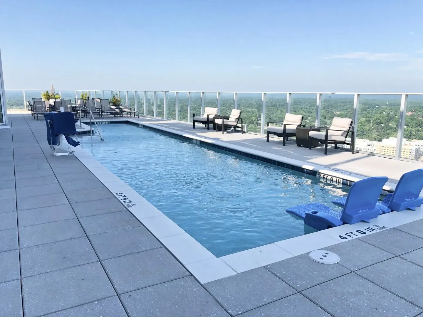 Rooftop swimming pool with lounge chairs and city views.