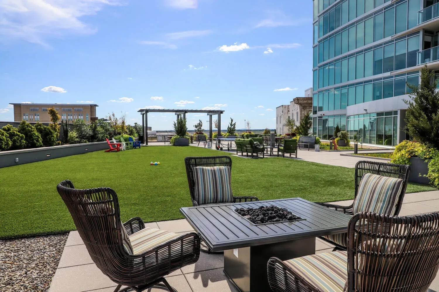 Rooftop patio with fire pit, seating, and artificial turf lawn.