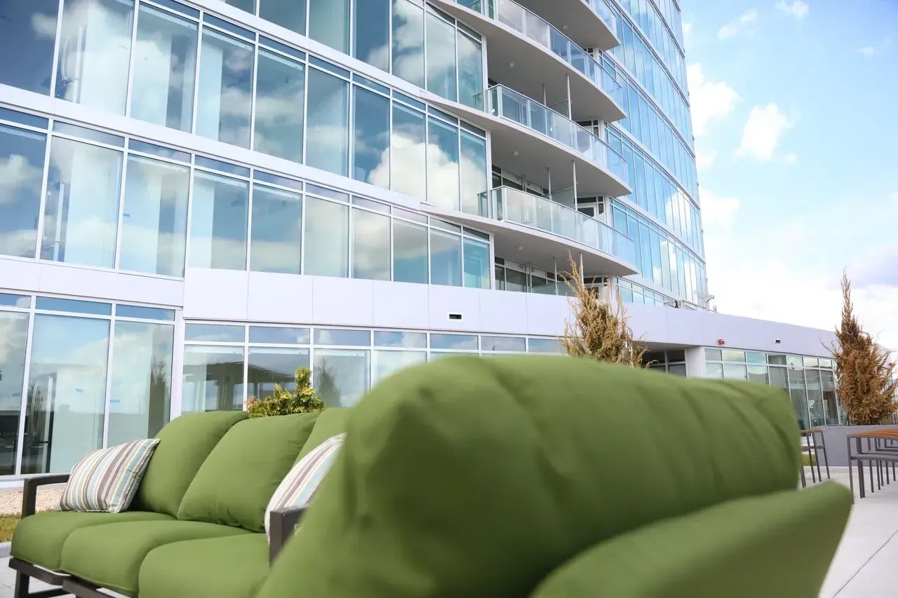 Modern apartment building with balconies and a green outdoor sofa in the foreground.