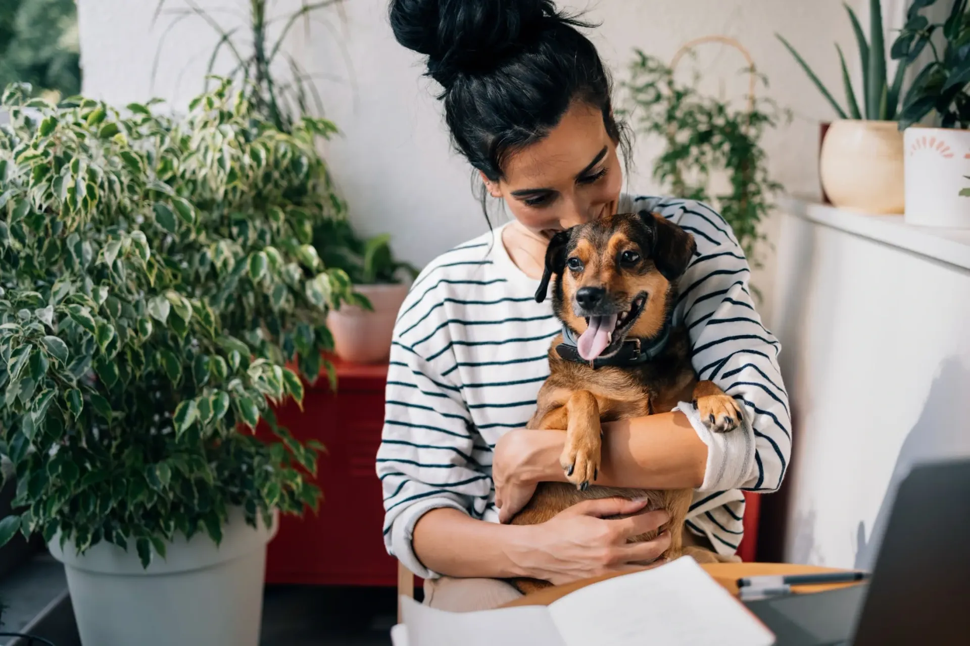 Woman holding a dog with plants in the background