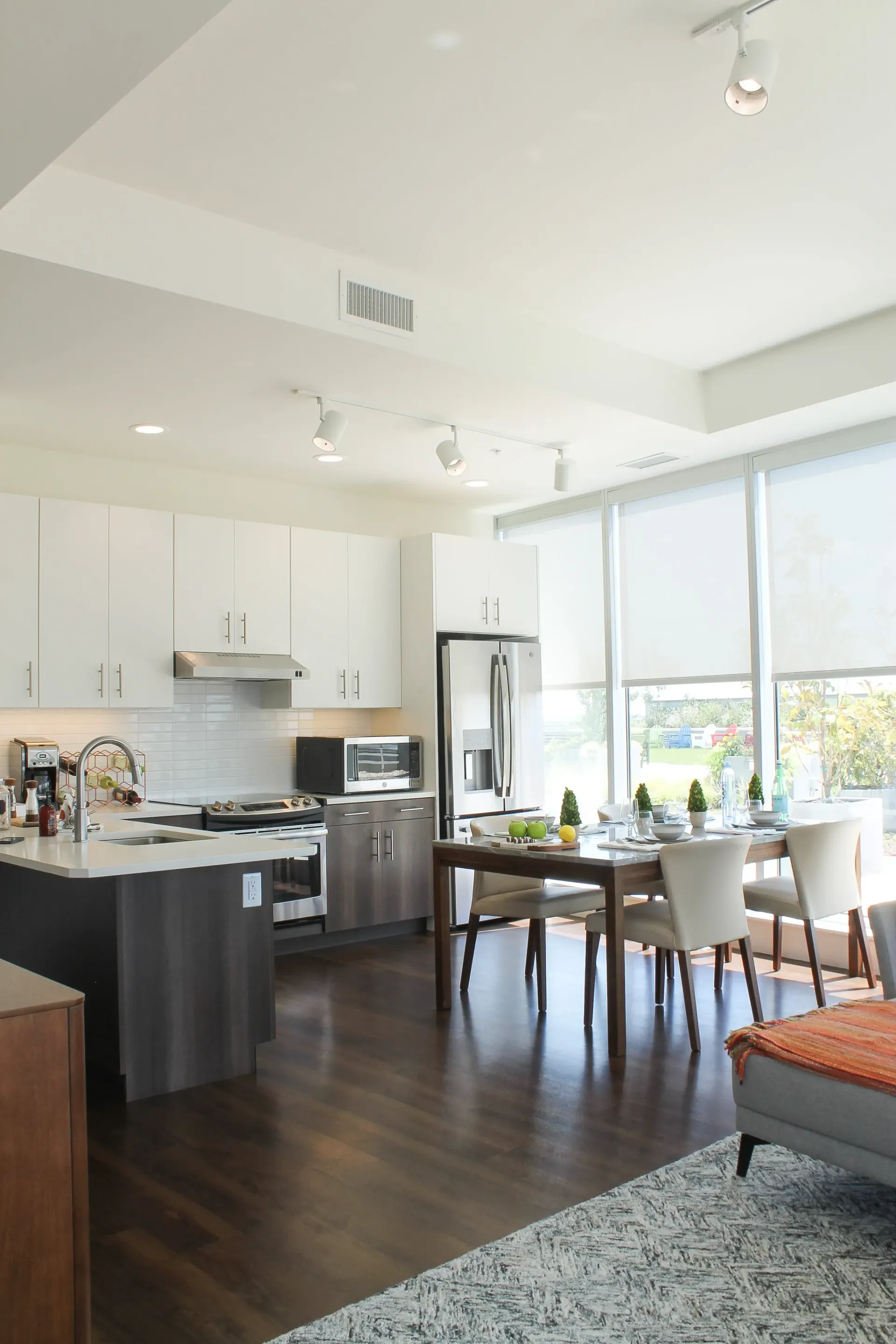 Modern kitchen and dining area with stainless steel appliances, white cabinets, and a dining table set for a meal.