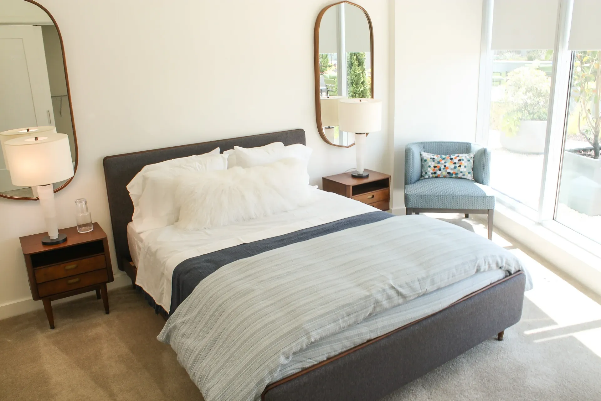 A bedroom with a king-size bed, nightstands, and a chair by the window.