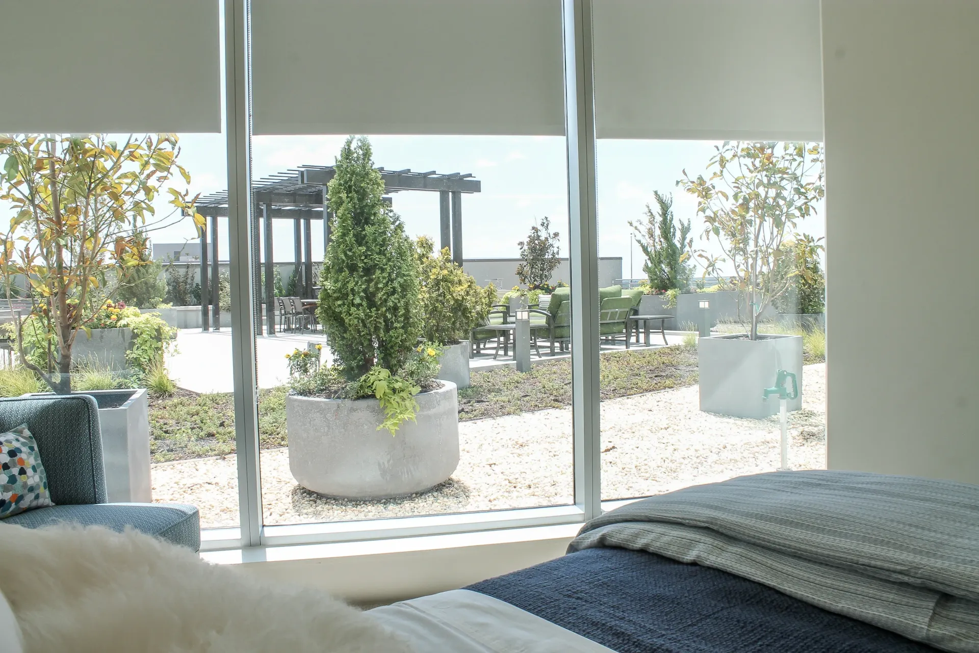 View of a rooftop courtyard with seating areas and planters from an apartment.