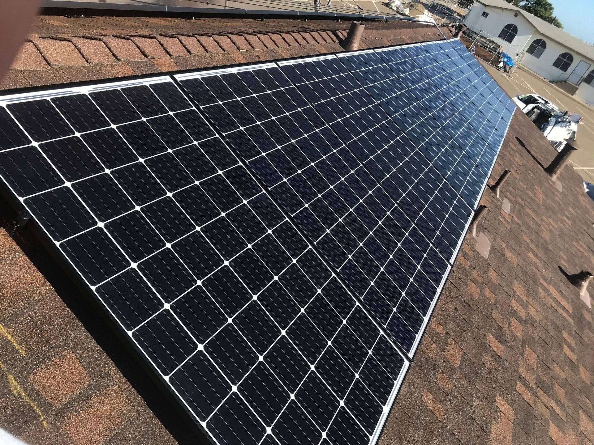 Rows of black solar panels installed on a tiled rooftop under daylight.