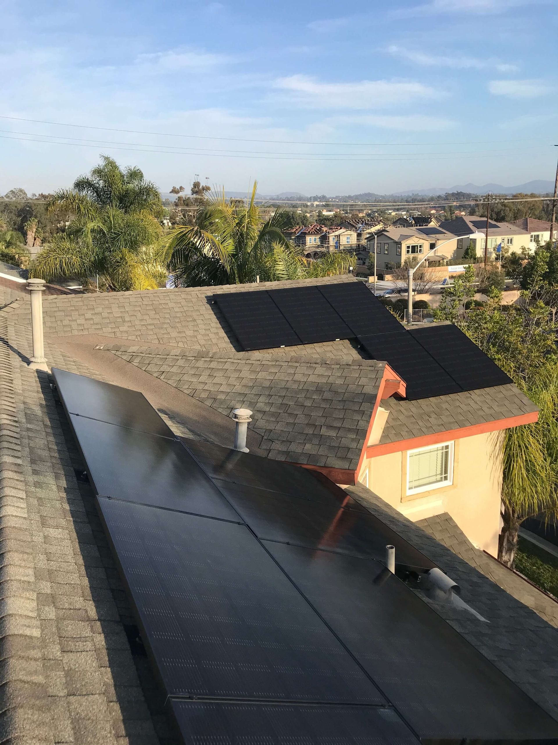 Rooftops in a suburban neighborhood at sunset, with a clear sky and distant houses.